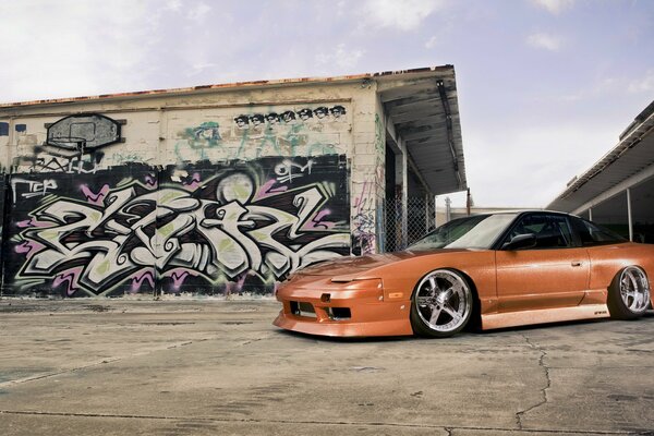 Tuned Nissan 240sx on the background of a wall with graffiti