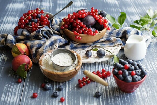 Pommes, bleuets et groseilles sur la table avec de la farine et du lait