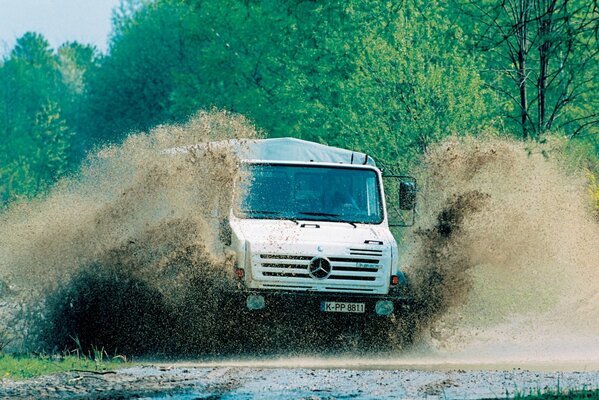 The truck is driving at high speed through a puddle. splashes