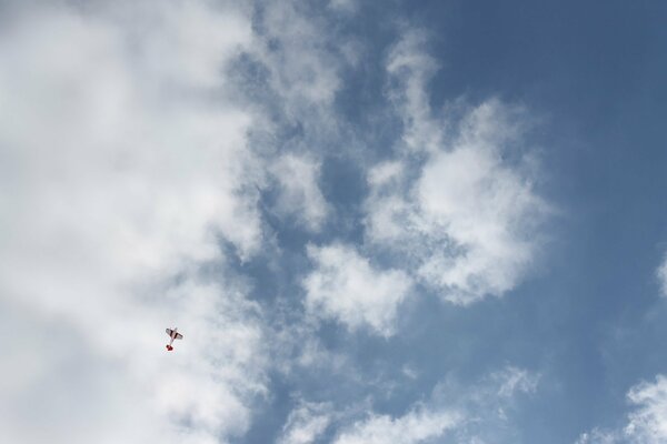 Flugzeug vor dem Hintergrund von weißen Wolken und blauem Himmel