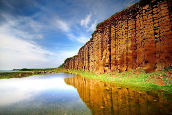 A huge red rock next to the lake