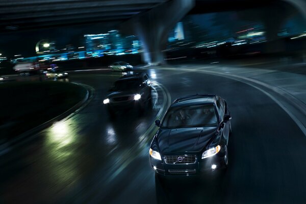 A black car rushes along the highway at night