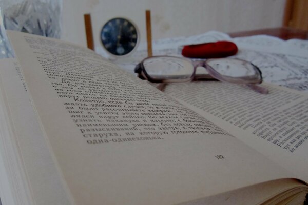Otwarta książka z okularami i zegarem w tle