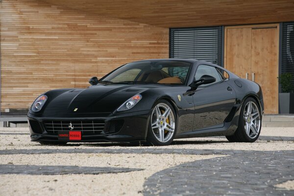 Ferrari negro en un edificio de madera