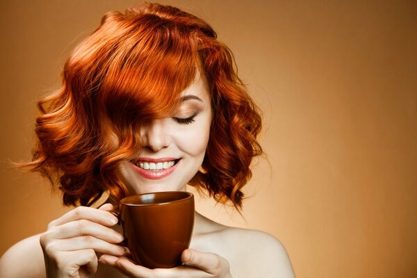 A red-haired girl with a gorgeous smile drinks coffee