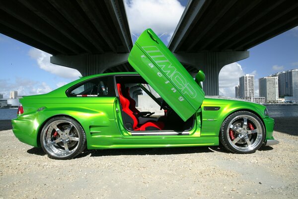 Green BMW with open lambo doors under the bridge in the city