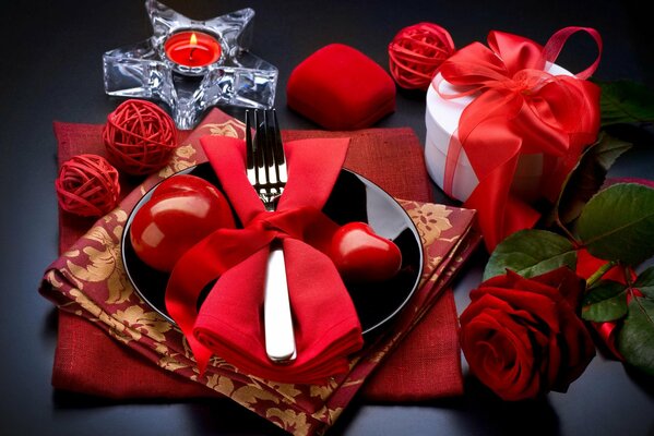 Table setting in red with rose and candle