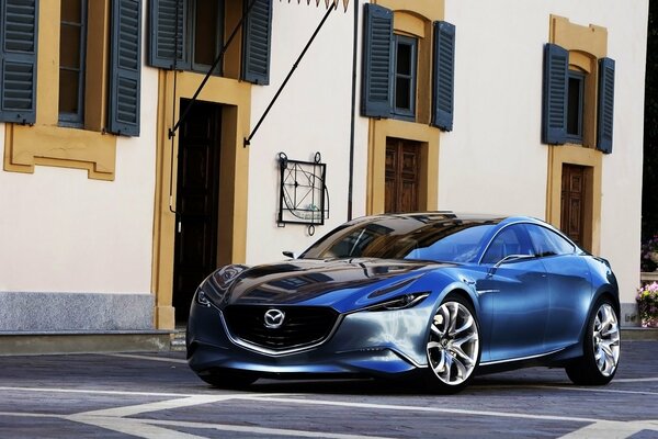 Photo of a blue mazda - shinari on the background of a building