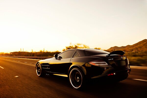 Mercedes benz negro monta en la puesta del sol