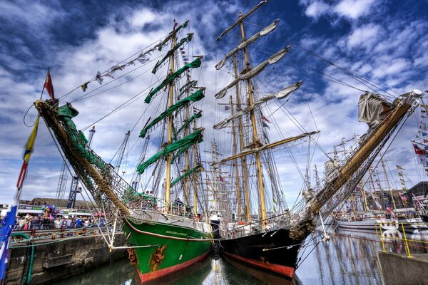 Yachts with green and white sails at the pier