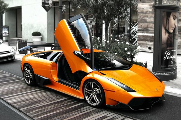 Оранжевый Lamborghini с открытой дверьюна серой улице