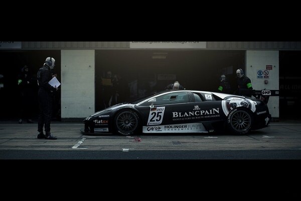 A black supercar with a spoiler stopped at the pit stop