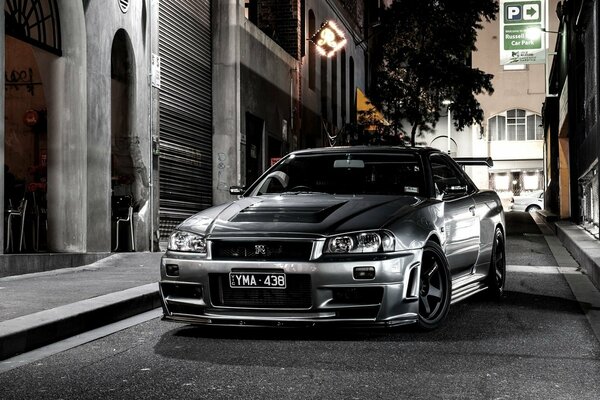 Nissan gris en la ciudad. Calle nocturna