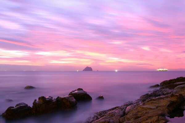 A ship on the horizon of a pink sunset