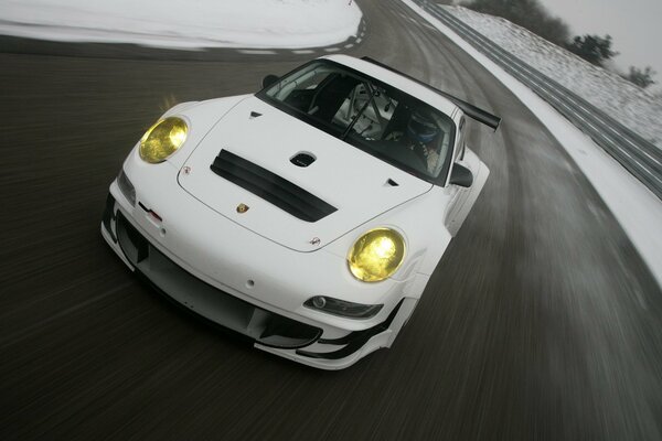 A white Porsche rushes along an empty highway