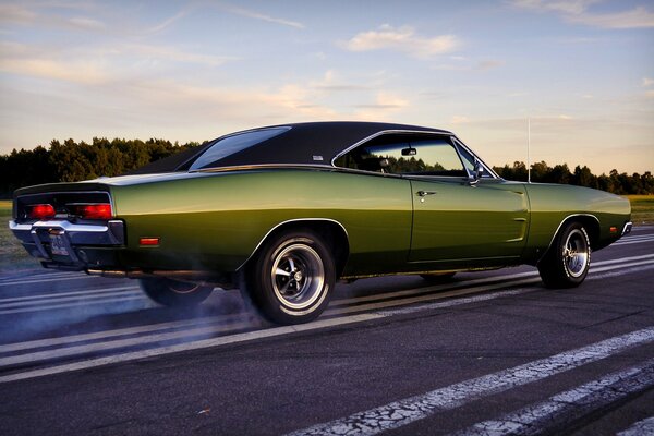 A green car is driving on the roadway