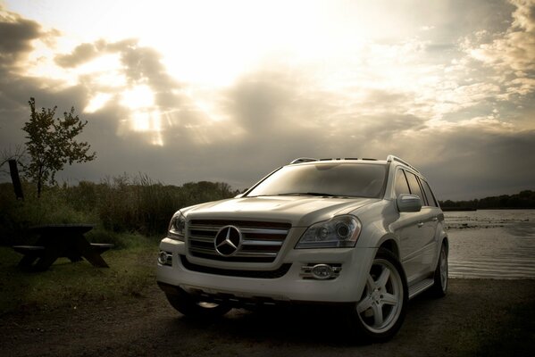 White Mercedes near a cloudy river