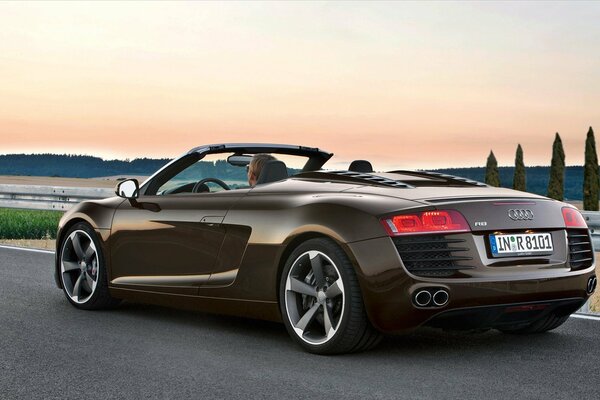 A brown Audi is standing on the road with a broken wheel