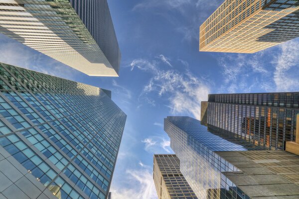 Hohe Wolkenkratzer in New York, die in den Himmel hineingehen und Wolken in den Gläsern reflektieren