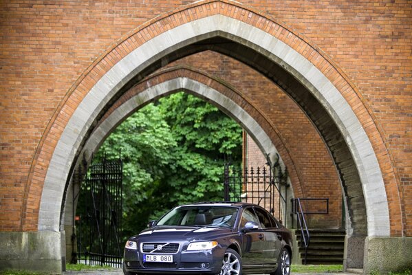 A Volvo car stopped under an arch of an unusual shape