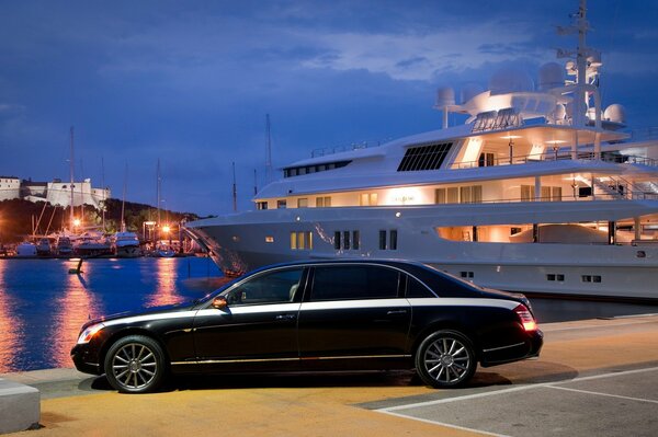 Auto nera di lusso sullo sfondo di un grande yacht bianco