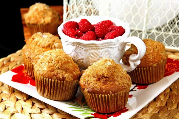 Muffins auf einem quadratischen Teller mit Himbeeren in einer Tasse