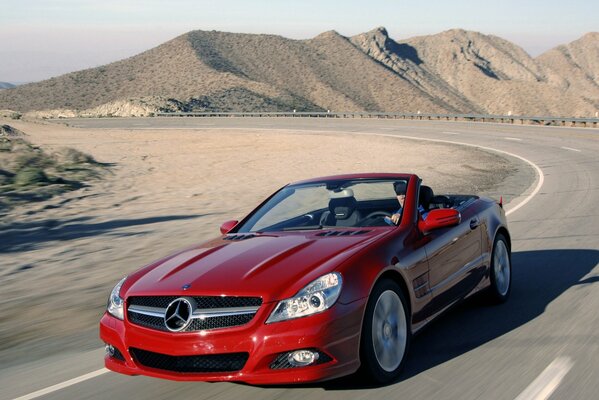 A red car on the road among the dunes