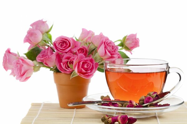 A bouquet of roses and a cup of tea on a saucer decorated with flower buds