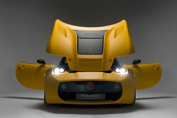 Mocny, żółty samochód sportowy z włączonymi reflektorami na szarym tle. Piękny