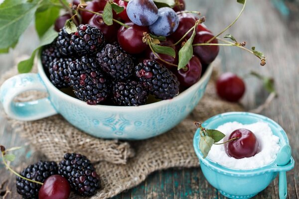 Stillleben mit Brombeeren und Kirschen in einer blauen Schüssel