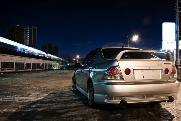 A shiny new car is standing in the dark of the night city, rear view