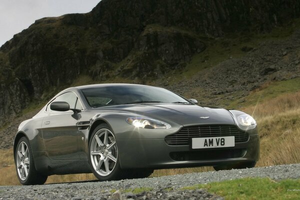 Aston Martin V8 grigio sullo sfondo delle montagne