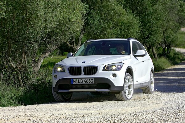 A white bmw car is driving on a dirt track