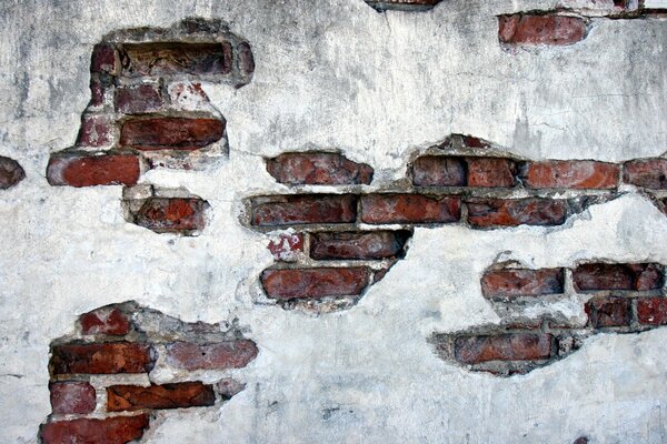 Vieux mur de briques rouges recouvert de plâtre