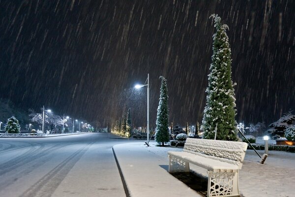 Night street in the first snow and in the light of lanterns