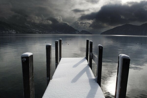 Un lago de invierno con un muelle indujo tristeza