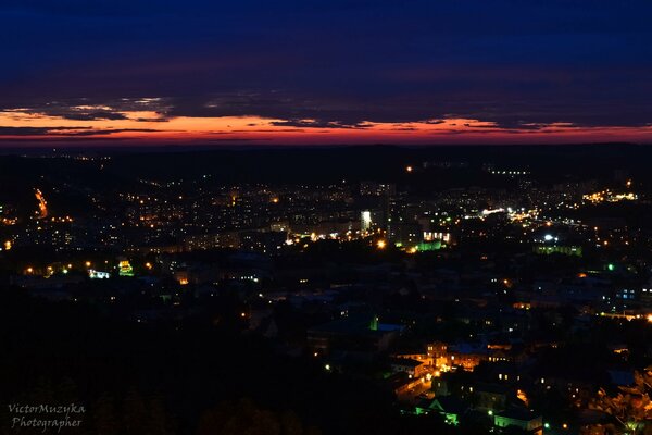 Puesta de sol sobre la ciudad nocturna con nubes naranjas