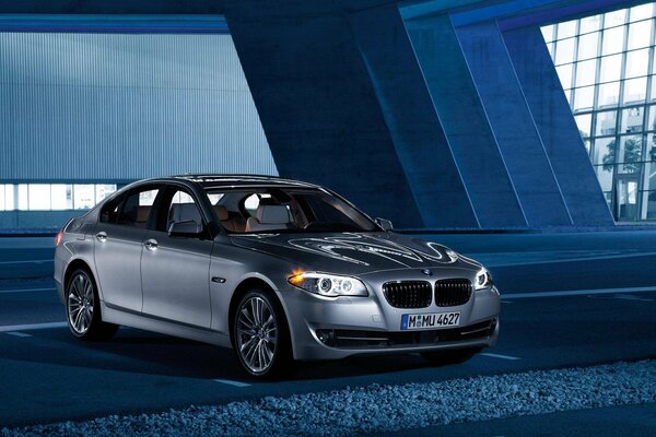 Szare BMW stoi w ogromnej przestrzeni z dużymi oknami
