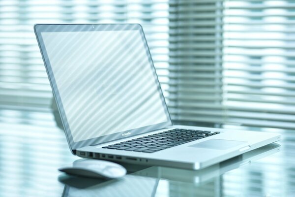 Laptop and mouse on the table on the background of the window