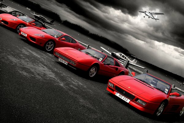 Four red cars in a cloudy sky