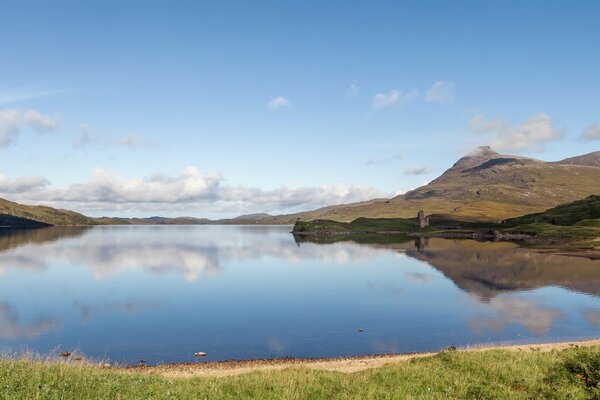 Szkockie jezioro między wzgórzami. Chmury odbijają się