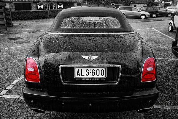 Expensive Bentley with red headlights in the parking lot in B/w