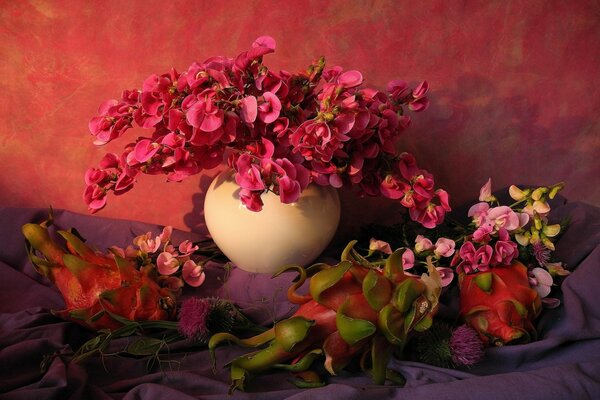 Still life with fruits and flowers on a red background