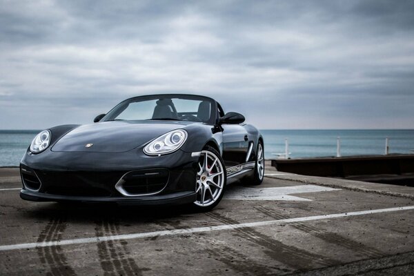 Schwarzer Porsche auf farbigem Meerhintergrund