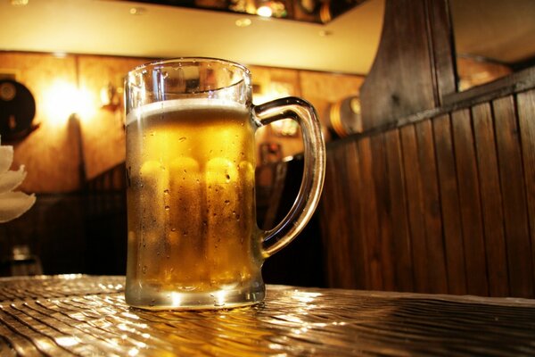Grande tasse de bière froide sur la table au bar