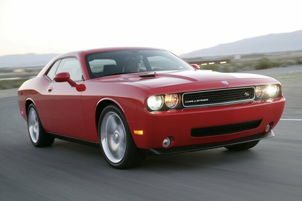 A red luxury car is driving on the road