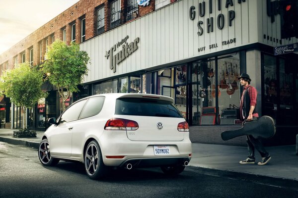 The man bought a guitar and goes to a white Volkswagen