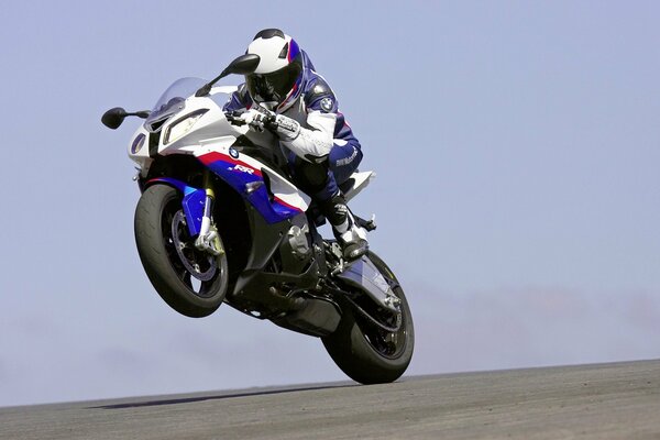 Athlete motorcyclist in a white and blue suit at the race