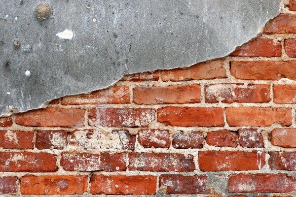 Vieux mur de briques rouges recouvert à moitié de plâtre