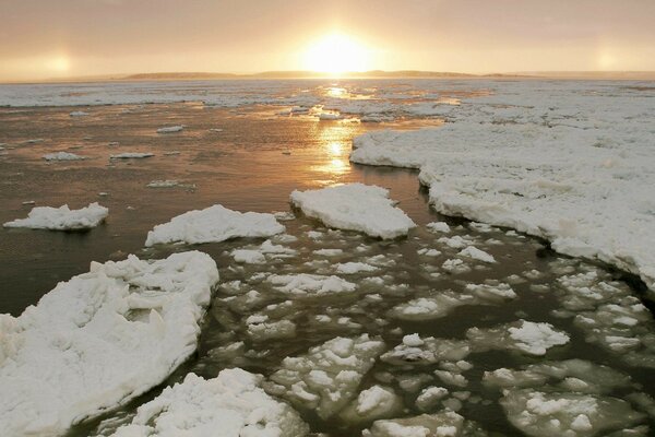 Der Fluss, darin ist Wasser mit Eis und die Sonne geht in den Sonnenuntergang